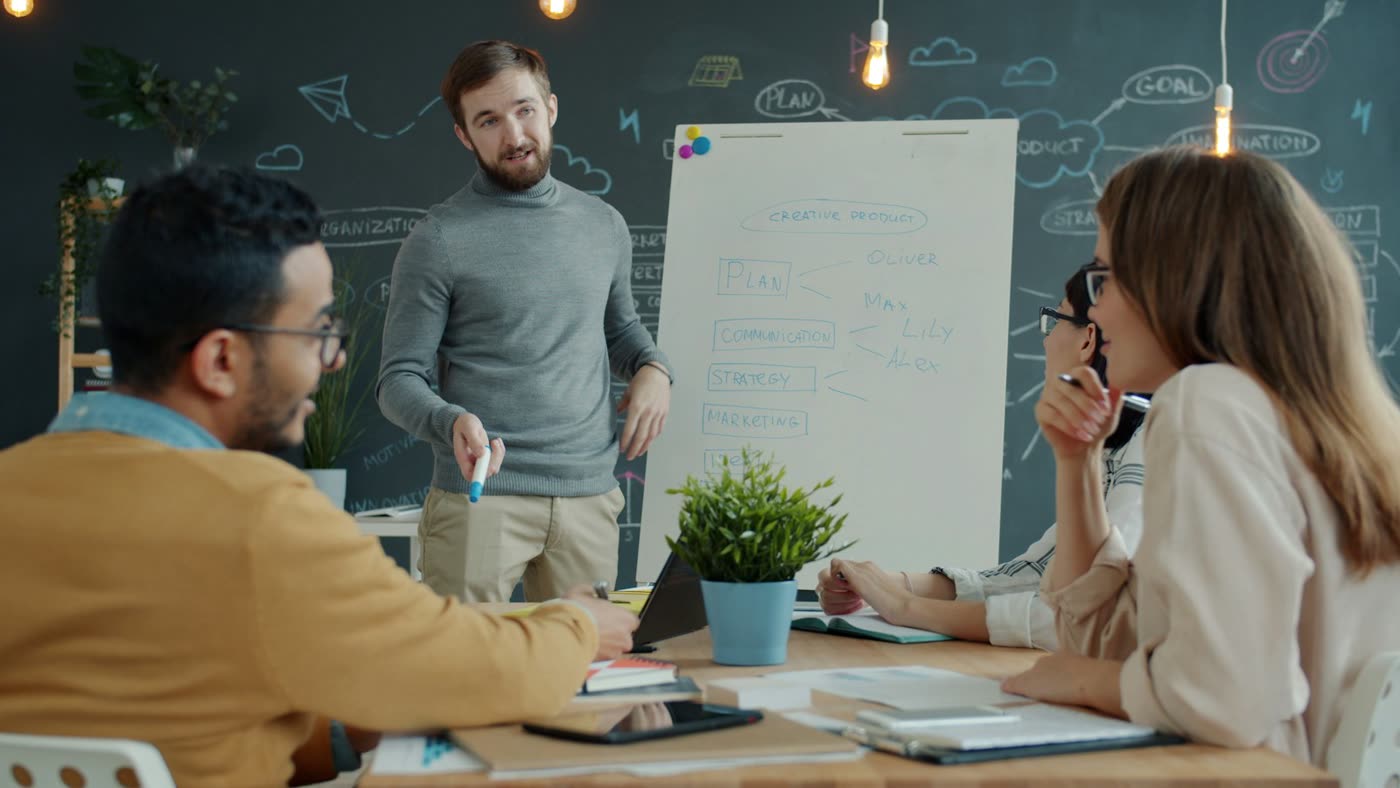 Tim menyusun strategi di depan whiteboard